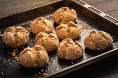 Homemade spelt bread rolls with salt on baking sheet