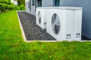 Yeni ve modern şehir evinin dışına yerleştirilmiş iki hava kaynağı ısı pompası, yeşil yenilenebilir enerji kavramı ısı pompası