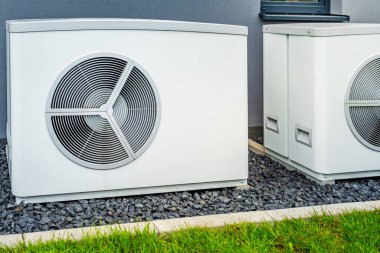Yeni ve modern şehir evinin dışına yerleştirilmiş iki hava kaynağı ısı pompası, yeşil yenilenebilir enerji kavramı ısı pompası