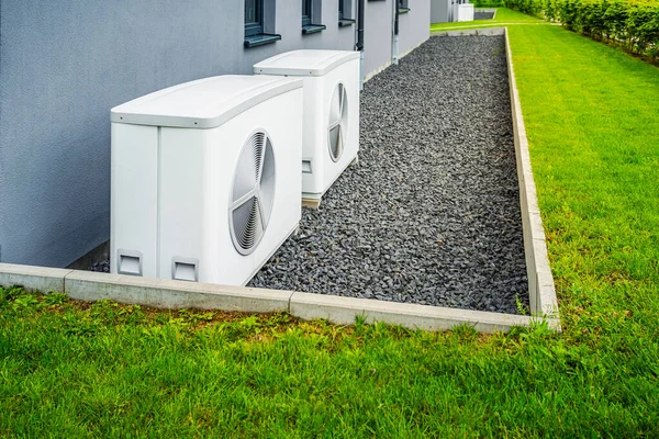 Two air source heat pumps installed outside of new and modern city house, green renewable energy concept of heat pump