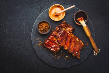 Barbekü domuz pirzolası ve siyah arka planda sıcak bal biberli terbiye.