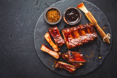 Barbekü domuz pirzolası ve siyah arka planda sıcak bal biberli terbiye.