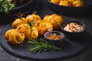 Ek otlar, baharatlar ve çırpılmış feta soslu Hasselback patatesleri.