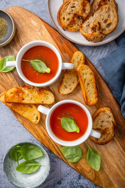 自制番茄汤 用罗勒 吐司和橄榄油装饰在木板上 — 图库照片