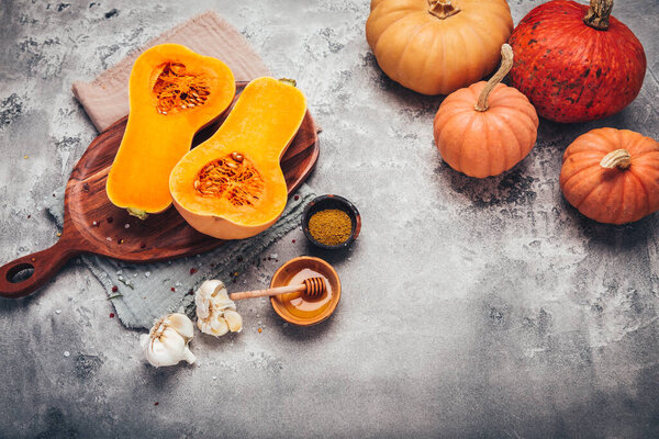 Halves of raw organic butternut squash with spices and ingredients for cooking