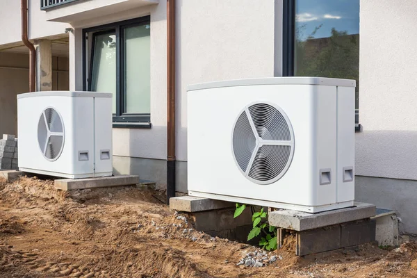 建設中の新しい近代的な都市の家の外に取付けられている2つの空気源のヒート ポンプ ヒート ポンプの緑の再生可能エネルギーの概念 — ストック写真