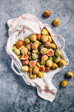 Gri arka planda sepetten taze toplanmış organik yeşil incirler.