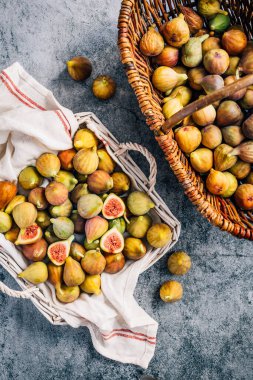 Gri arka planda sepetten taze toplanmış organik yeşil incirler.