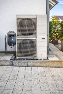 Modern aile evinin dışına yerleştirilmiş iki hava kaynağı ısı pompası, yeşil yenilenebilir enerji konsepti ısı pompası