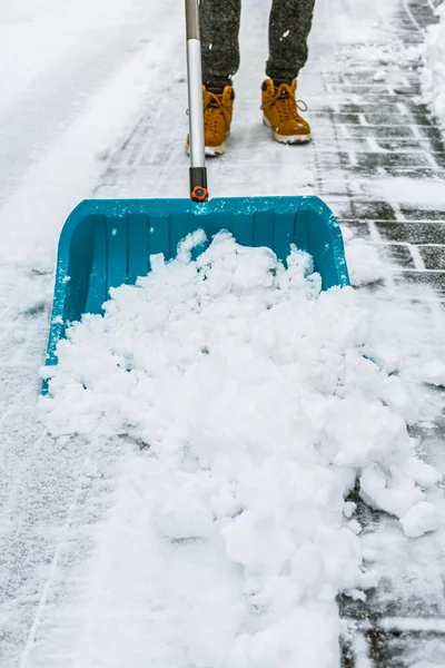 Cleaning snow from street in winter with shovel after snowstorm. Cleaning sidewalk from snow on a winter day.