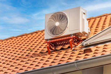 Dual inverter compressor, combination of air conditioner compressor and heating pump, installed on a roof of family house. clipart