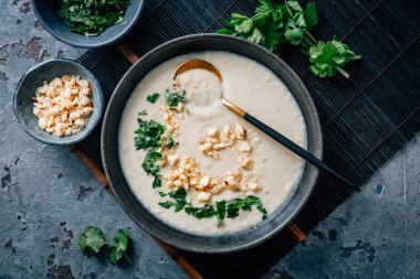 Spicy and creamy cauliflower and coconut soup with cilantro and macademia nuts clipart