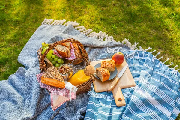 異なる食べ物 フルーツ オレンジジュース 緑の草のヨーグルトとパンとピクニックデュベットとバスケット ストック画像