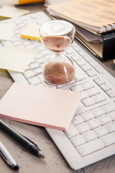 Stock image Crop of hourglass on home office table count measure time.  Workplace of busy employee, time management and burnout concept