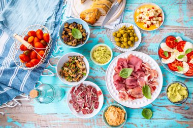 Çeşitli aperatiflerle piknik masası, çiğ sebze, peynir, sos, baget, pastırma ve serrano tabağı.