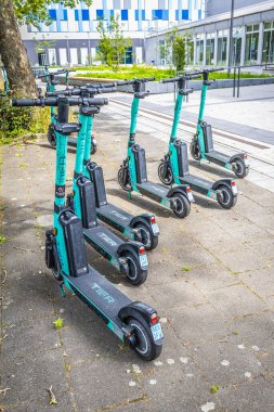 Tier kiralık elektrikli scooter 'lar şehrin modern binasının önüne park edilmiş.