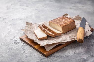 Mutfak masasında bıçakla tütsülenmiş organik tofu.