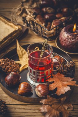 Soğuk sonbahar günleri için meyve çayı, sonbahar yapraklı kestaneler ve eski kitaplar.