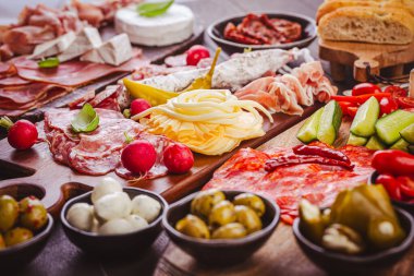 Ahşap tepside çeşitli aperatifler ve antipasti tabakları et ve peynirle servis konsepti.