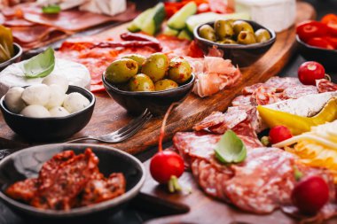 Ahşap tepside çeşitli aperatifler ve antipasti tabakları et ve peynirle servis konsepti.