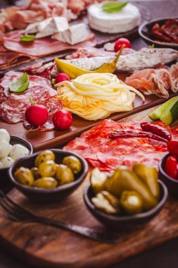 Ahşap tepside çeşitli aperatifler ve antipasti tabakları et ve peynirle servis konsepti.