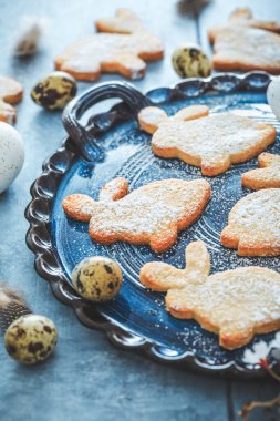 Paskalya için ev yapımı bademli tavşan kurabiyesi ve mavi tonda Paskalya yumurtası.