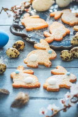 Paskalya için ev yapımı bademli tavşan kurabiyesi ve mavi tonda Paskalya yumurtası.