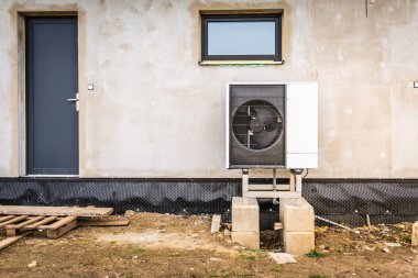 Yeni bir aile evinin duvarına ısı pompası yerleştiriyorum.