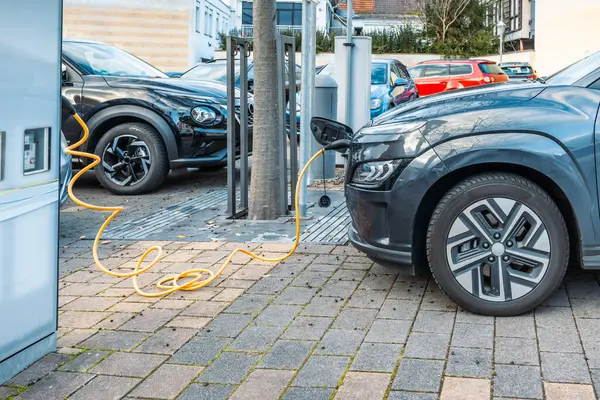 Şehirdeki halka açık park alanında modern elektrikli arabaları şarj etmek