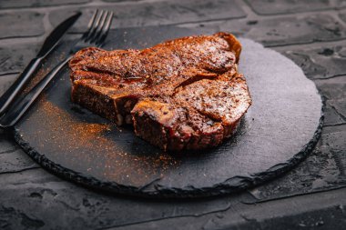 Biftek ve siyah servis tabağında baharat.