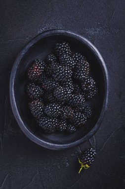 Bahçeden yeni toplanmış organik böğürtlenler siyah arka planda bir kasede