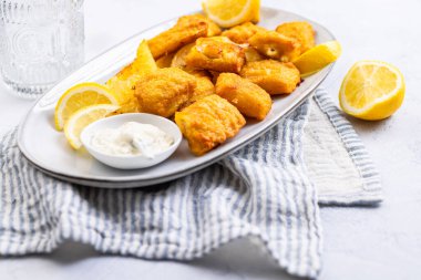 Servis tabağında limon ve tartar soslu geleneksel balık ve patates kızartması