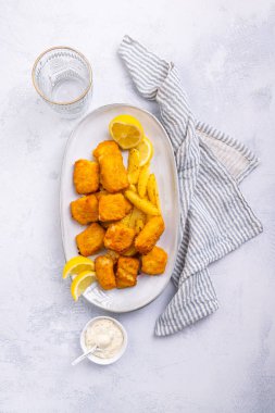 Servis tabağında limon ve tartar soslu geleneksel balık ve patates kızartması
