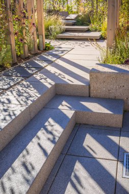 Farklı alanları birbirine bağlayan basamakları olan veranda, çağdaş bahçe manzarası