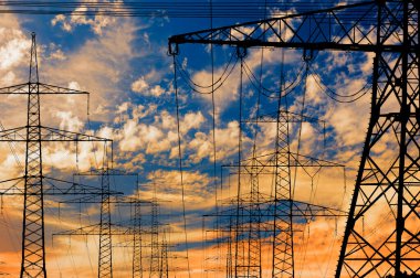 Elektrik ve elektrik için yüksek voltajlı sütunlar dramatik bulutlarla gökyüzüne karşı
