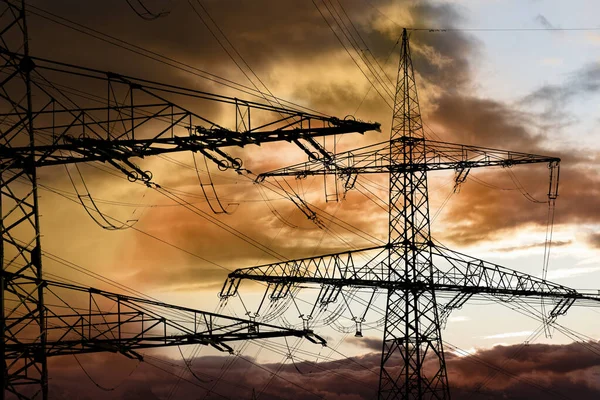 Elektrik ve elektrik için yüksek voltajlı sütunlar dramatik bulutlarla gökyüzüne karşı