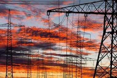 Elektrik ve elektrik için yüksek voltajlı sütunlar dramatik bulutlarla gökyüzüne karşı