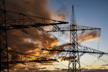 Elektrik ve elektrik için yüksek voltajlı sütunlar dramatik bulutlarla gökyüzüne karşı