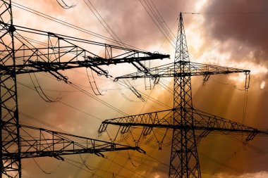 Elektrik ve elektrik için yüksek voltajlı sütunlar dramatik bulutlarla gökyüzüne karşı