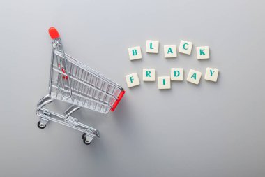 Black friday text and shopping cart on the gray background. Top view. clipart