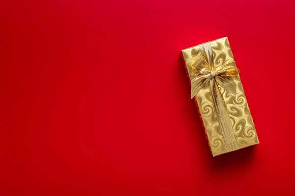 用金箔包裹的礼物 圣诞礼物 红色背景上有金丝带 顶部视图 — 图库照片