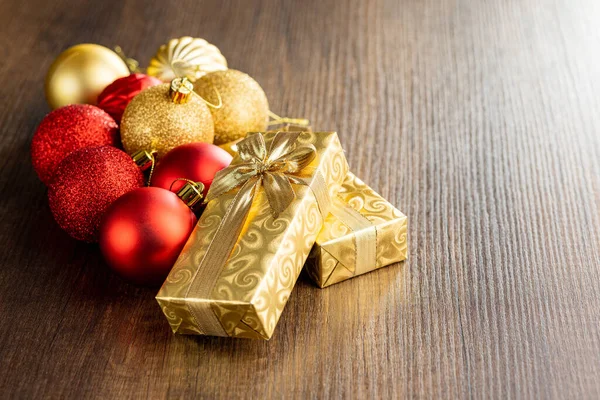 Δύο Χρυσά Χριστουγεννιάτικα Δώρα Και Χριστουγεννιάτικες Μπάλες Στο Ξύλινο Τραπέζι — Φωτογραφία Αρχείου