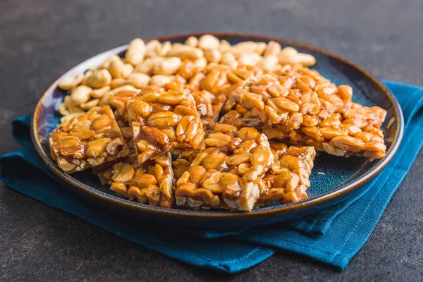 Sweet peanut brittle. Tasty peanuts in caramel on the plate.