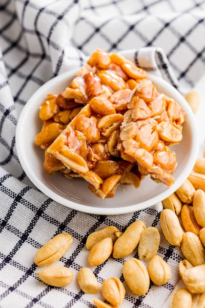 Sweet peanut brittle. Tasty peanuts in caramel on the checkered napkin.