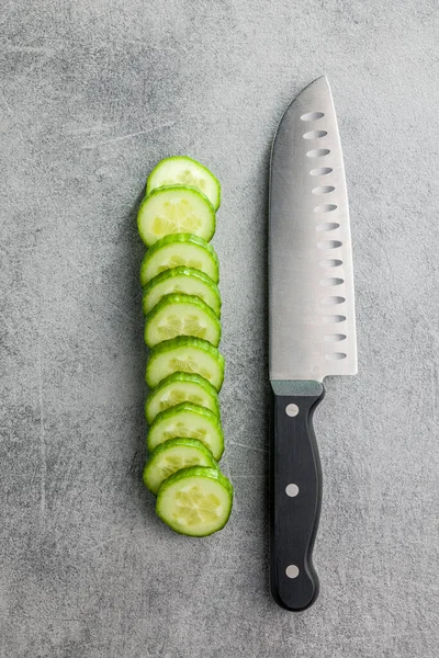 キッチンテーブルの上で新鮮な緑のキュウリとナイフをスライスしました トップ表示 — ストック写真