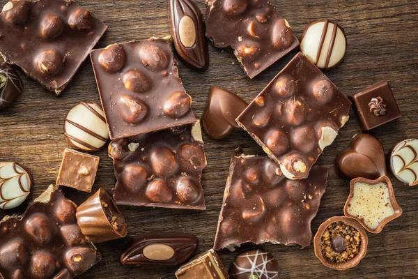 Gebroken Chocoladerepen Met Nootjes Pralines Houten Tafel Bovenaanzicht — Stockfoto