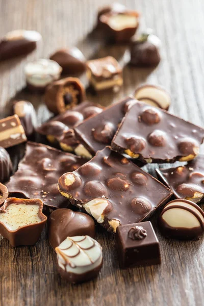 木のテーブルの上にナッツとプラリネと壊れたチョコレートバー — ストック写真