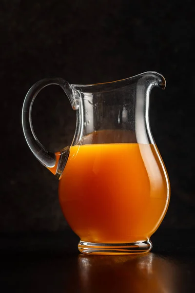 フルーツジュースのピッチャーボトル 黒テーブルの上のオレンジジュース — ストック写真