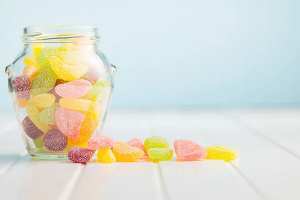 Mix of fruity jelly candy in jar on the white table.