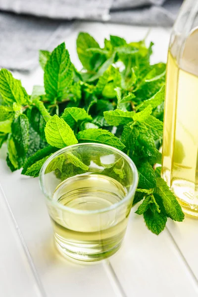 Sweet mint syrup and mint leaves on the white table.